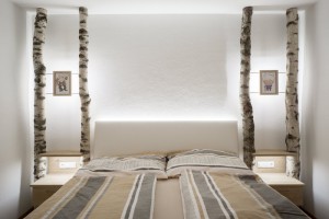 Schlafzimmer mit zimmerhohen Birkenstämmen